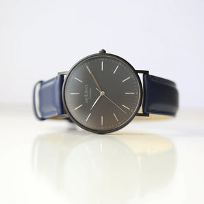 A men's watch with a stainless steel case in polished/brushed finish and a blue genuine leather strap, featuring a minimalist dial design.