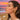 Woman wearing gold plated conch shaped earrings with a beach and sunset in the background