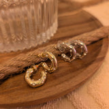 Gold plated half hoop earrings with cubic zirconia on a wooden surface