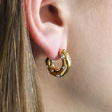 Gold plated hoop earring with small cubic zirconia worn by a person