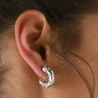 Stainless steel half hoop earring with cubic zirconia, worn on a female ear