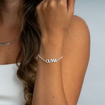 Custom Silver bracelet with 'OLIVIA' on a person's wrist against a neutral background