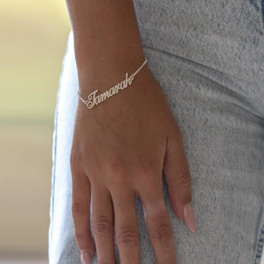 Custom silver name bracelet on a wrist against a blurred background