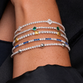 Stack of colorful beaded bracelets on a wrist against a black background