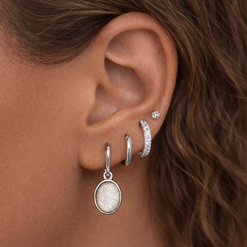 Close-up of an ear wearing multiple silver earrings with a blurred background