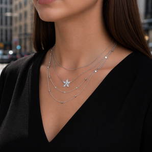 Urban Pizazz Model Wearing Sterling Silver & Cubic Zirconia Flower Necklace, layered with other silver chain necklaces on a busy street setting