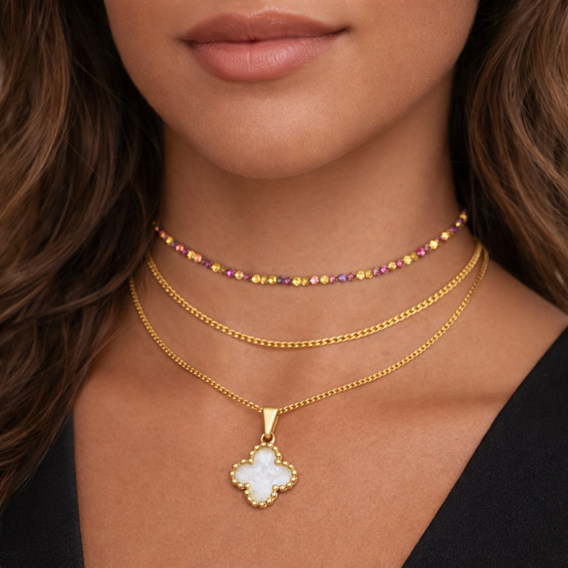 Close-up of a woman wearing multiple gold necklaces with a central pendant.